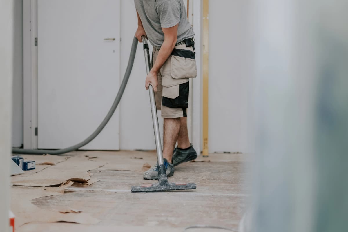 Worker vacuuming dust and debris during post-construction cleaning in a London property renovation