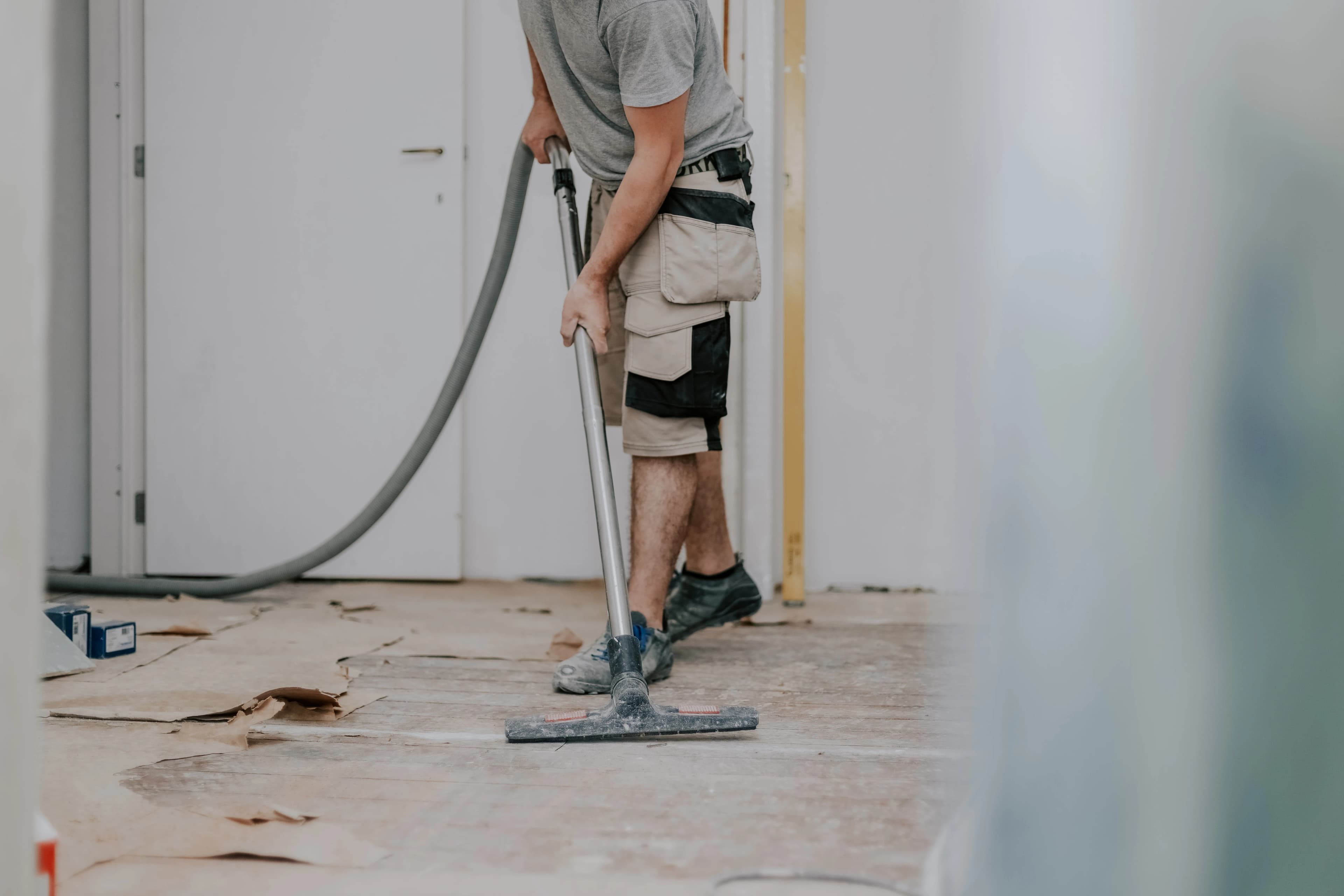 Worker vacuuming dust and debris during post-construction cleaning in a London property renovation